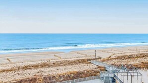 Une vue sur la plage avec une promenade en bord de mer, une plage de sable et l’océan.
