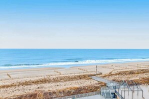 Blick auf einen Strand mit Promenadenweg, Sandstrand und dem Meer.