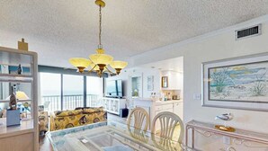 Ein modernes Wohnzimmer mit einem Glastisch, einem gelben Sofa und einer Chandelier.