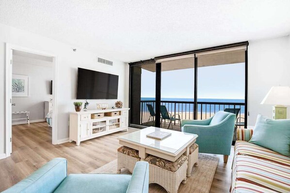 A living room with a TV, a sofa, a coffee table, and a view of the sea. - Sea Colony Ocean 5th floor condo w/ shared sauna, elevator, and pool (Bethany Beach)