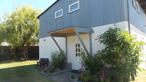 A two-story house with a porch, a door with a window, and a bench.