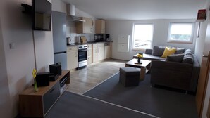 A modern kitchen with built-in appliances, a dining area with a sofa and coffee table, and a large window providing natural light.