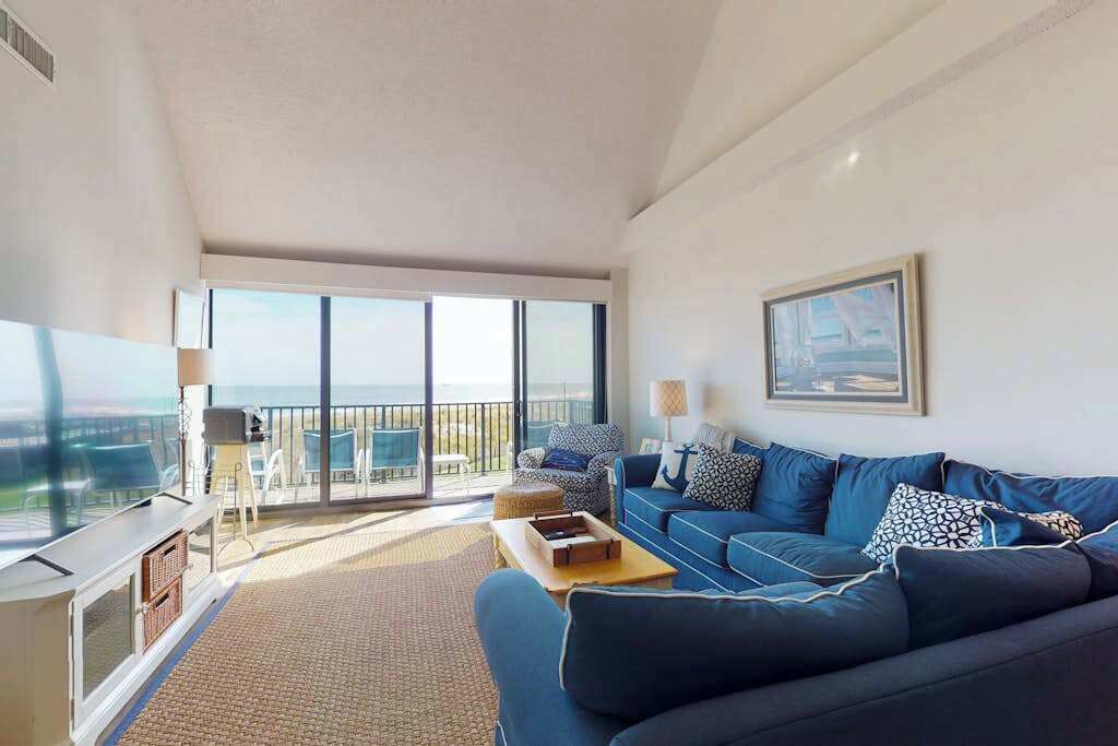 Un soggiorno moderno con un divano blu, una TV a schermo piatto e un balcone con vista.