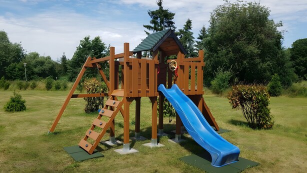 A wooden playground structure with a slide and climbing elements.