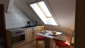 A compact kitchen with a skylight, a dining table with chairs, and a radiator.