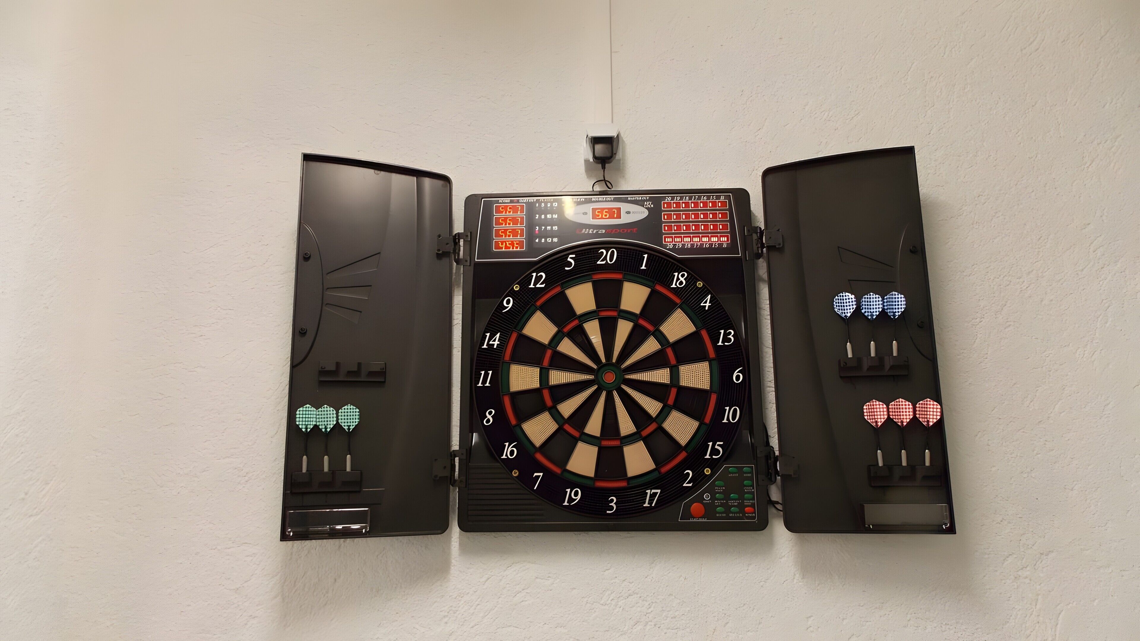 A dartboard mounted on a wall with a digital score display above it.