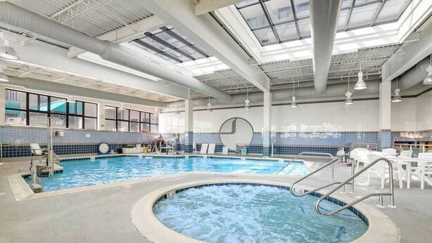 An indoor swimming pool with a hot tub, clear ceiling, and tiled walls. - Sea Colony Ocean 2nd floor condo with sauna (Bethany Beach)