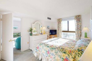 A hotel room with a bed, a television, a dresser, and a window with curtains. - Sea Colony Ocean 2nd floor condo with sauna (Bethany Beach)