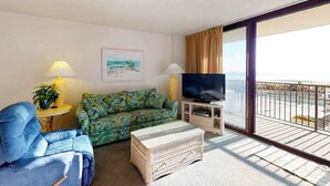 A living room with a sofa, a television, a lamp, and a balcony with a view. - Sea Colony Ocean 2nd floor condo with sauna (Bethany Beach)