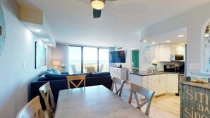 Ein modernes Wohnzimmer mit Essbereich, Küche und einem Balkon mit Blick.