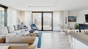 Uma sala de estar moderna com sofá, poltronas, mesa de centro e área de jantar com mesa e cadeiras.