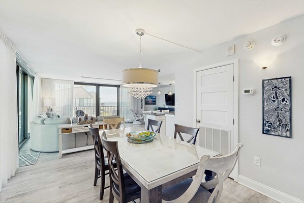A modern dining area with a white table, chairs, and a chandelier. - Sea Colony Ocean 2nd floor condo w/ elevator, gym, and free WiFi (Bethany Beach)