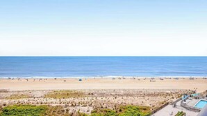 Vista a la playa con piscina y valla.