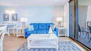 Una sala moderna con un sofá azul, una mesita de centro blanca y dos mesitas auxiliares con lámparas.