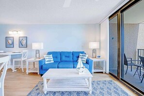 Ein modernes Wohnzimmer mit einem blauen Sofa, einem weißen Couchtisch und zwei Beistelltischen mit Lampen.