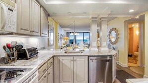 A modern kitchen with a built-in dishwasher, a large island with a sink, and a view to the living area. - Sea Colony Ocean 6th floor condo w/ pool, gym, and free WiFi (Bethany Beach)
