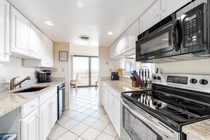 Una cocina moderna con armarios blancos, estufa, microondas y pileta.
