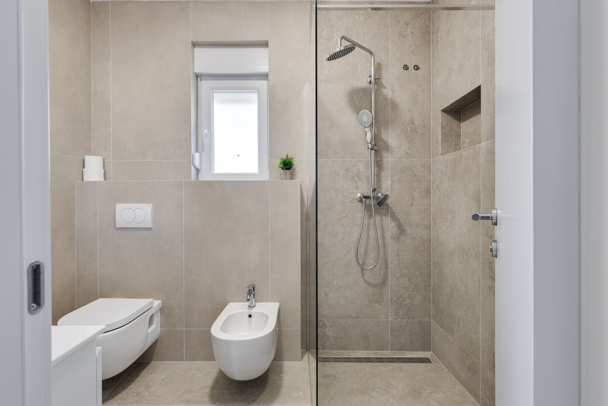 Et moderne badeværelse med toilet, bidet og brusebad.