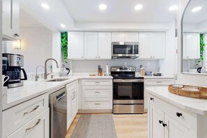 A modern kitchen with white cabinets, stainless steel appliances, and a built-in microwave. - Sea Colony Ocean 7th floor condo with indoor/outdoor pools, tennis, & gym access (Bethany Beach)