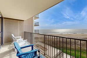 Een balkon met twee stoelen, een fles en uitzicht op het strand.