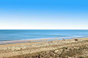 A beach with a clear sky, sandy dunes, and a small structure in the distance. - Sea Colony 6th floor condo w/ shared sauna, tennis court, and free WiFi (Bethany Beach)