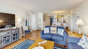 Un salon avec un canapé bleu, une table basse en bois et un téléviseur posé sur un meuble.