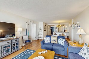 A living room with a blue sofa, a wooden coffee table, and a TV on a cabinet. - Sea Colony 6th floor condo w/ shared sauna, tennis court, and free WiFi (Bethany Beach)