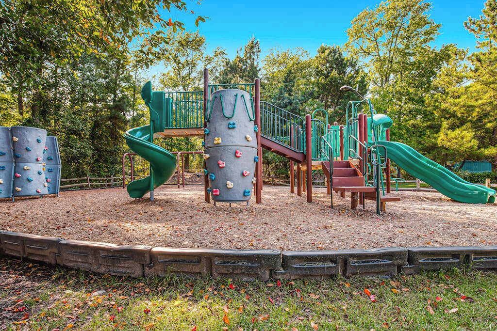 Un parque infantil con estructuras para escalar, toboganes y una valla de madera.