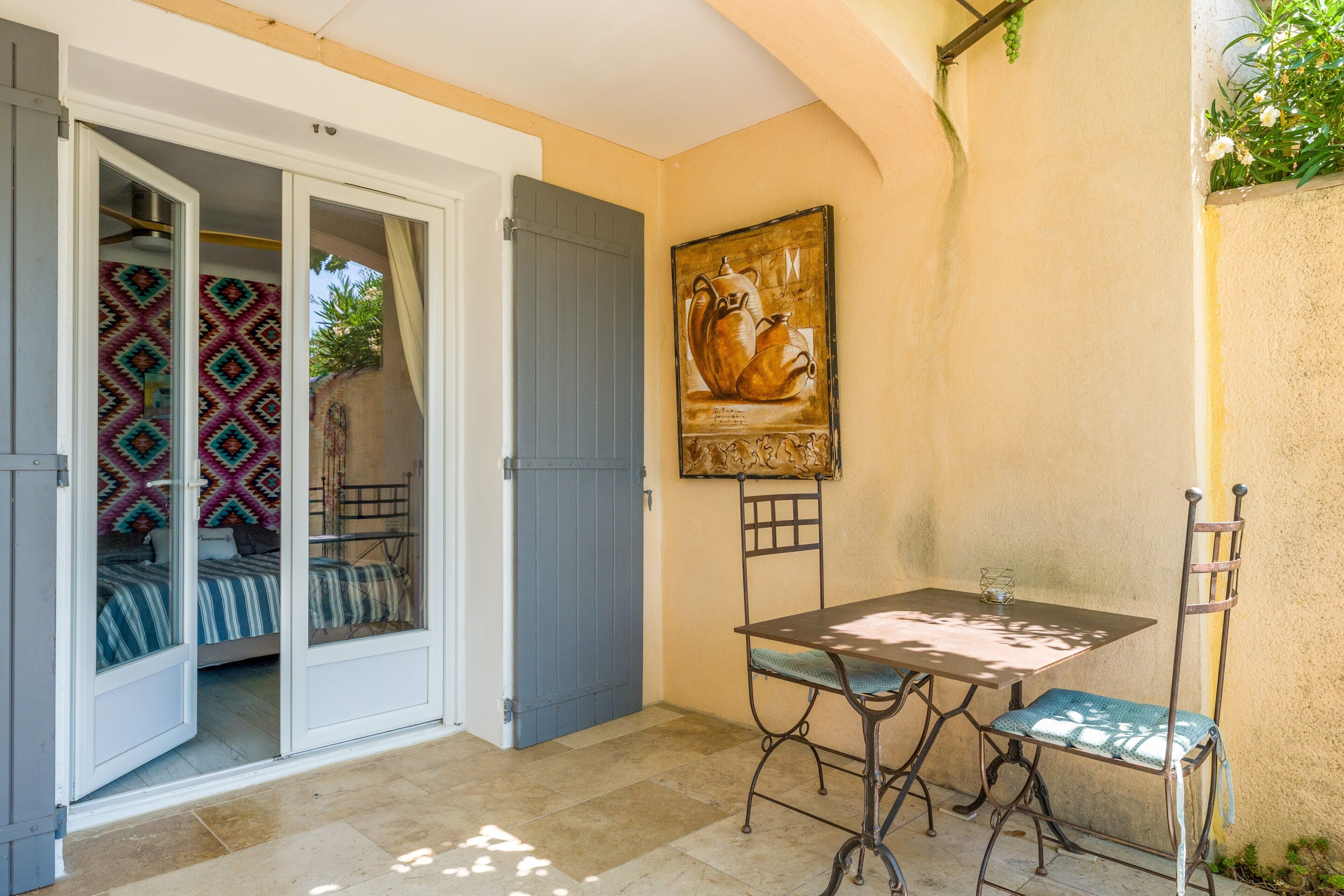 A room with a bed, a table with chairs, a door, and a wall with a painting.