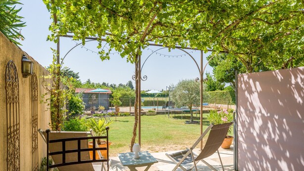 A patio with two chairs, a small table, and a pergola with string lights.