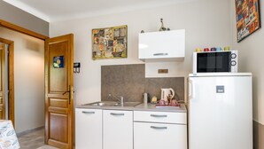 A compact kitchen with white cabinets, a microwave, a sink, and a coffee maker.