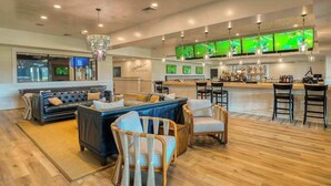 Un espace bar moderne avec des sièges, un comptoir et plusieurs écrans diffusant des événements sportifs.