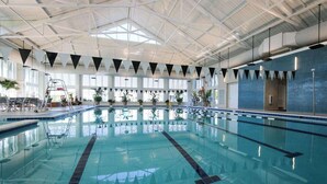 Une piscine intérieure avec des couloirs bien délimités, un échelle et une vue sur le ciel grâce à de grandes fenêtres.