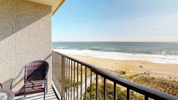 A balcony with a view of the beach, a chair, and a table. - Sea Colony Ocean 7th floor condo w/ gym, balcony, and tennis court (Bethany Beach)
