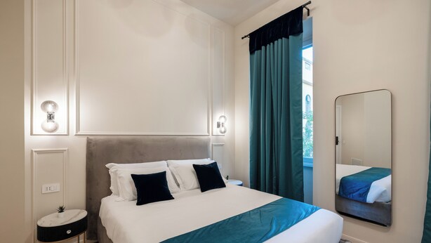 Une chambre d’hôtel bien rangée, avec un lit, une table de chevet et un miroir.