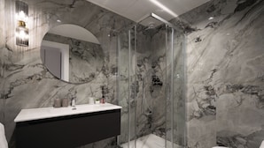 Une salle de bain moderne avec un mur en marbre, une douche en verre, un lavabo blanc et des toilettes.