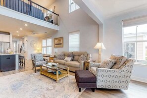 A spacious living area with a high ceiling, a balcony, a kitchen, and a dining area. - Dog-friendly resort townhouse w/shared sauna, fireplace, basketball/tennis court (Selbyville)