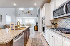 A modern kitchen with granite countertops, stainless steel appliances, and a view into the living area. - Dog-friendly resort townhouse w/shared sauna, fireplace, basketball/tennis court (Selbyville)