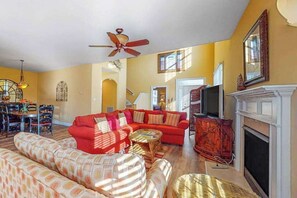 A living room with a red sofa, a patterned sofa, a fireplace, and a television. - Bayside Resort townhouse w/ free WiFi, tennis court, pool, and board games (Selbyville)