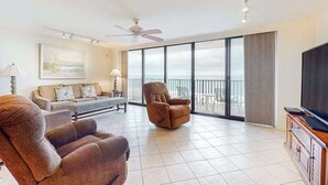 A spacious living room with a large TV, comfortable seating, and a balcony with a view. - Sea Colony Ocean 9th floor condo w/ balcony, gym, and free WiFi (Bethany Beach)