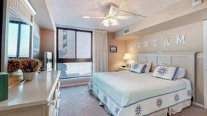 Een slaapkamer met een bed, een plafondventilator, een raam en een muur waarop het woord 'DREAM' staat.