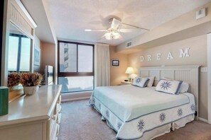Een slaapkamer met een bed, een plafondventilator, een raam en een muur waarop het woord 'DREAM' staat.