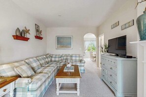 Ein Wohnzimmer mit einem Ecksofa, einem Couchtisch, einem Fernseher und einer Kommode.