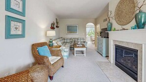 Una sala de estar con sofá, sillón, chimenea y elementos decorativos.