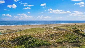 Et kystlandskab med strand, grønne områder og en klar blå himmel.