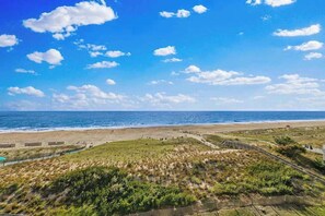 A coastal landscape with a beach, grassy areas, and a clear blue sky. - Sea Colony Ocean 5th floor condo w/ free WiFi, elevator, and balcony (Bethany Beach)