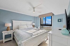 A bedroom with a bed, nightstands, a desk, a ceiling fan, and a window with a view. - Sea Colony Ocean 5th floor condo w/ free WiFi, elevator, and balcony (Bethany Beach)