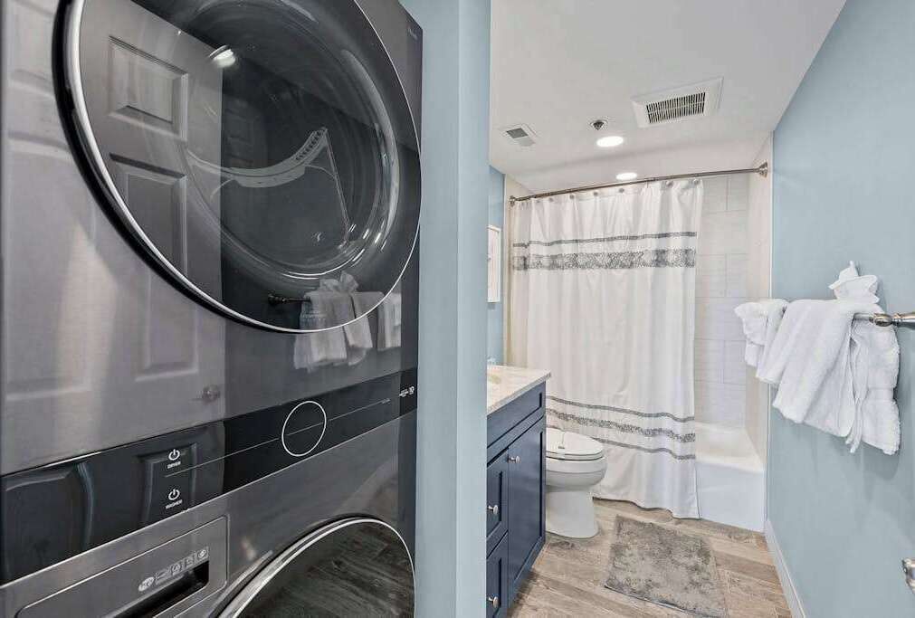 Un baño moderno con lavadora integrada, inodoro y zona de ducha.