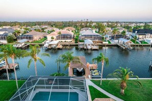 A marina with boats docked, surrounded by houses with docks, and a swimming pool in the foreground. - Gulfcoast Oasis - 910 Golf Island Dr 4 Bedroom Home (Apollo Beach)