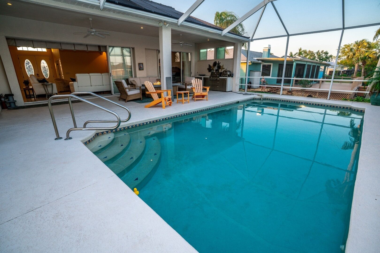 A swimming pool with a sun deck, lounge chairs, and a covered patio area.